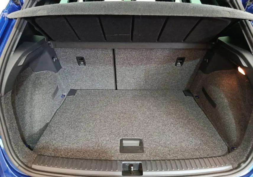 Vue arrière du coffre ouvert du SEAT Arona bleu 2021, montrant l'espace de rangement et la tablette de séparation.