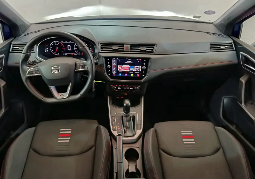 Vue intérieure avant du tableau de bord et des sièges noirs avec surpiqûres rouges du SEAT Arona 2021 finition FR.