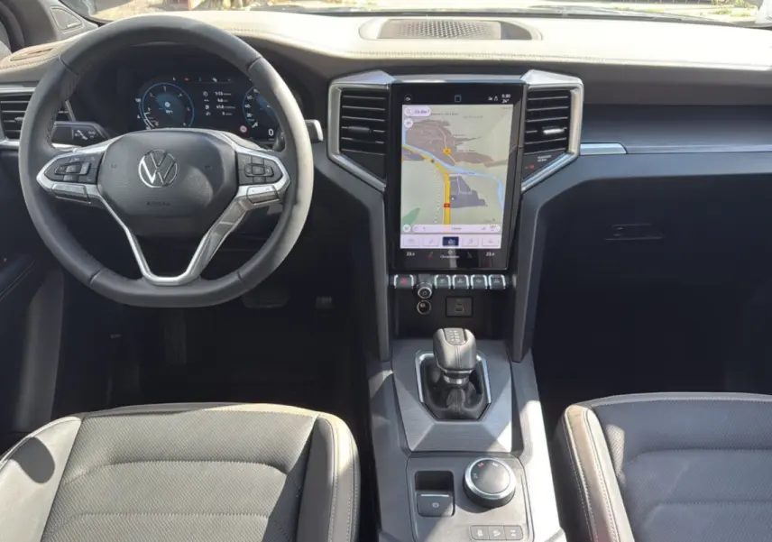 Vue intérieure frontale du tableau de bord du Volkswagen Amarok Simple Cabine 2025, avec écran tactile vertical et volant multifonction.