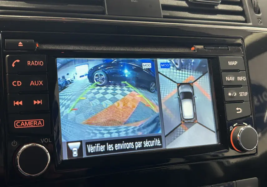 Écran de caméra 360° affichant la vue arrière et aérienne d'une Nissan Pulsar grise en stationnement intérieur.