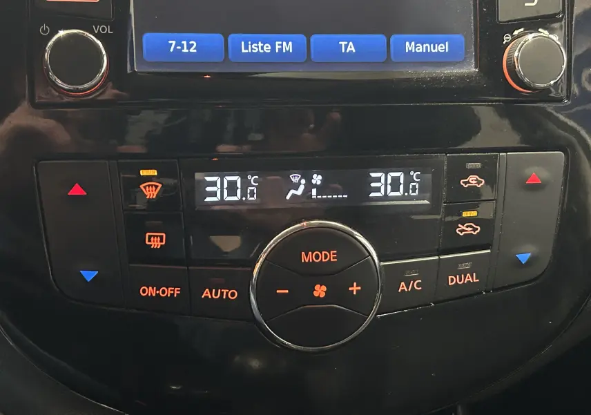 Gros plan sur la console centrale noire de la Nissan Pulsar 2018, affichant la climatisation digitale à 30°C en mode dual.