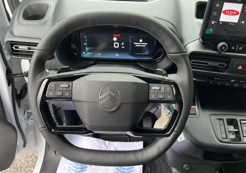 Vue rapprochée du volant cuir multifonctions et du tableau de bord numérique du Citroën Berlingo Kaolin White 2026.