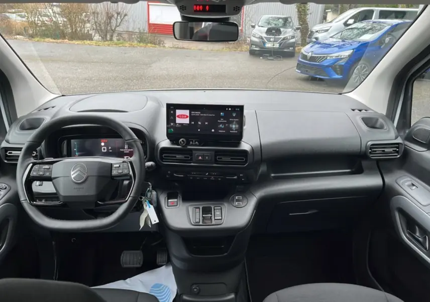 Vue intérieure frontale du Citroën Berlingo blanc, tableau de bord moderne avec écran tactile central et volant multifonctions.