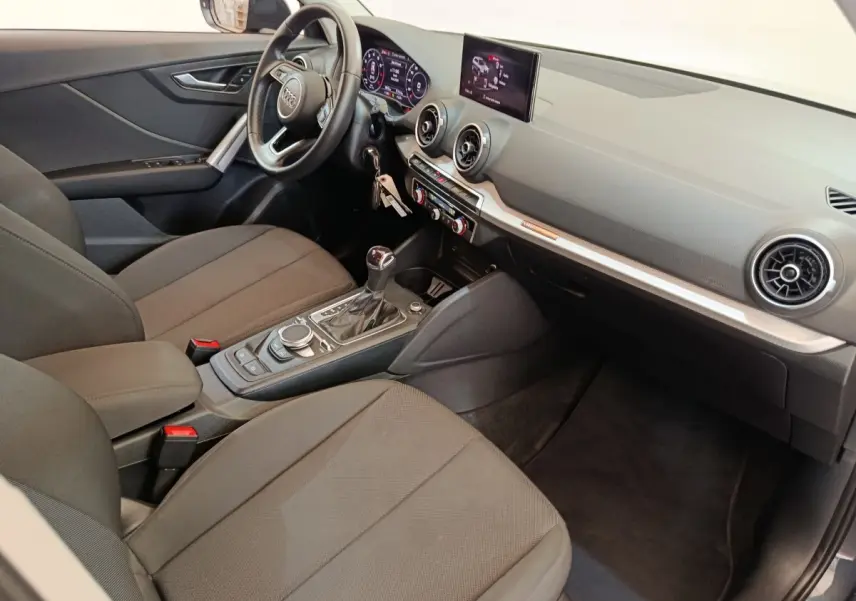 Intérieur avant droit de l'Audi Q2 gris foncé 2022, avec tableau de bord digital et console centrale moderne.