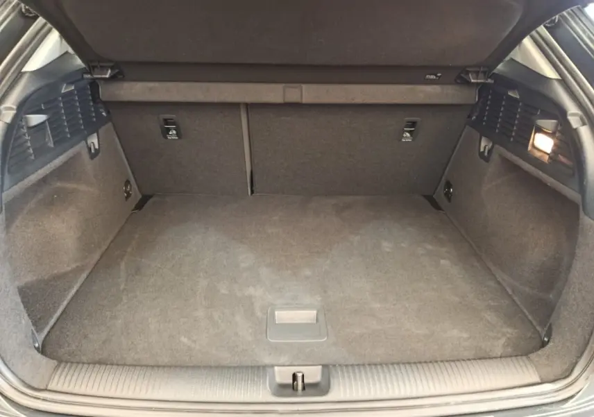 Vue intérieure du coffre spacieux et propre de l'Audi Q2 gris foncé, avec banquette arrière rabattable visible.