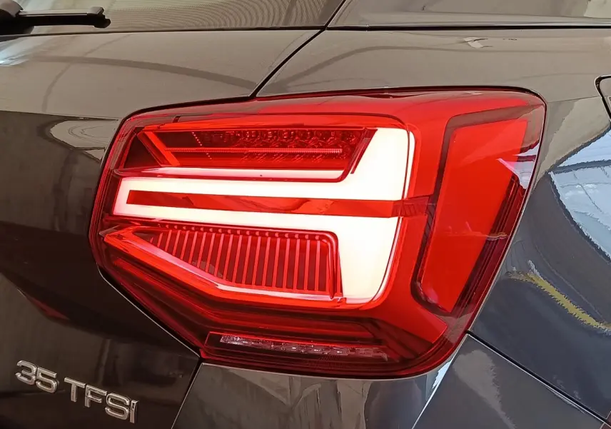 Gros plan sur le feu arrière droit rouge et blanc d’un Audi Q2 gris foncé 35 TFSI 150 S Tronic Business Line.