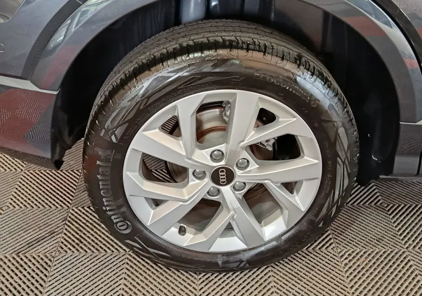 Gros plan sur la roue avant droite d’un Audi Q2 gris foncé, avec jante en alliage et pneu Continental.