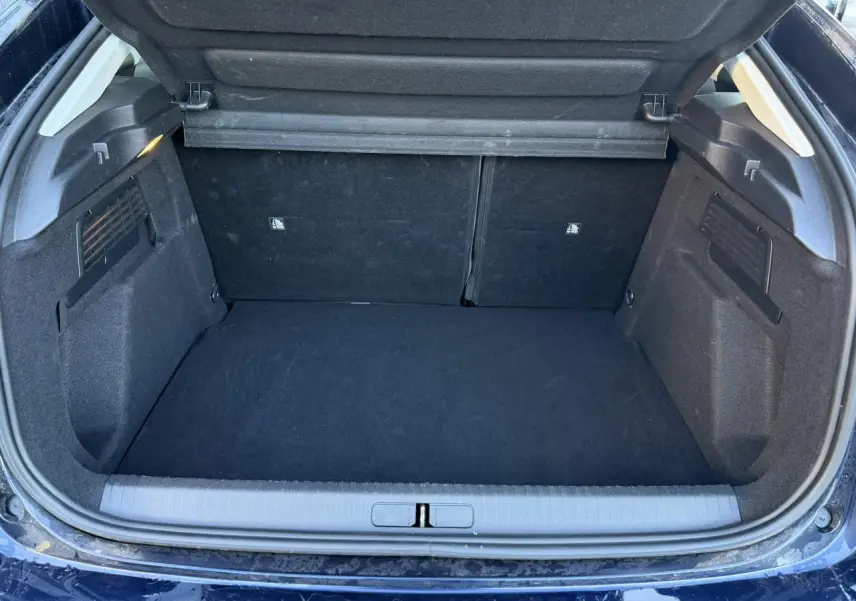 Coffre ouvert vu de l'arrière d'une Citroën C4 Hybrid 145 bleu Eclipse, espace de chargement vide et propre.