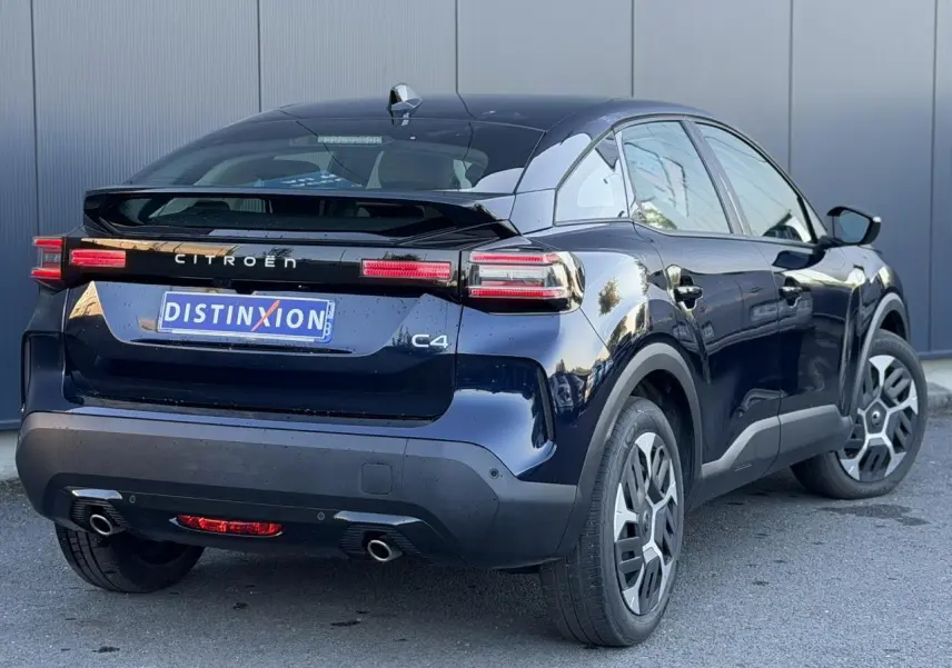 Vue 3/4 arrière droite d'une Citroën C4 Hybrid 145 bleu Eclipse avec feux arrière LED et double sortie d'échappement.