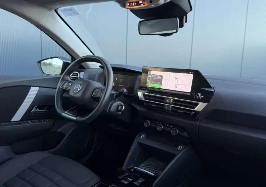 Intérieur avant de la Citroën C4 Hybrid 145, vue côté conducteur montrant le volant, tableau de bord et écran tactile central.