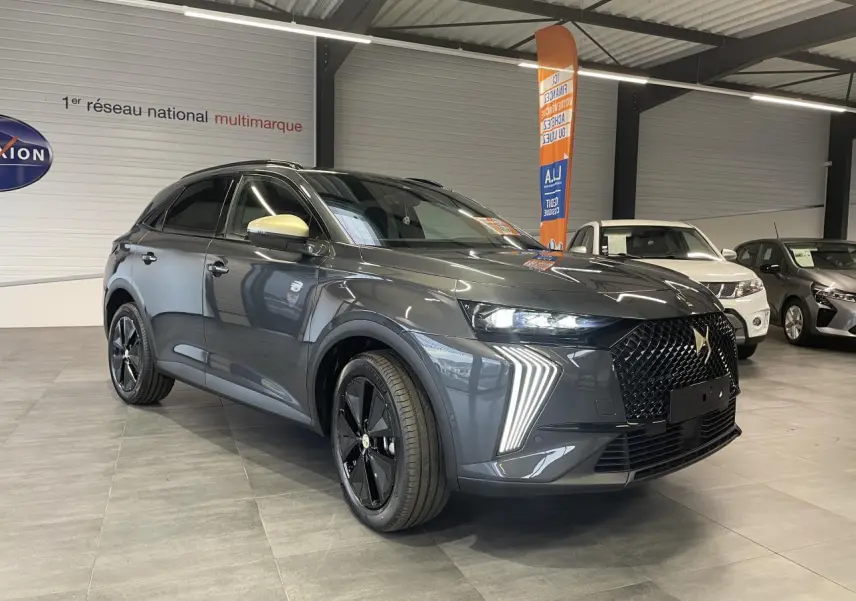 DS7 Crossback gris titanium en 3/4 avant droit, avec calandre noire brillante et feux LED distinctifs en forme de flèche.