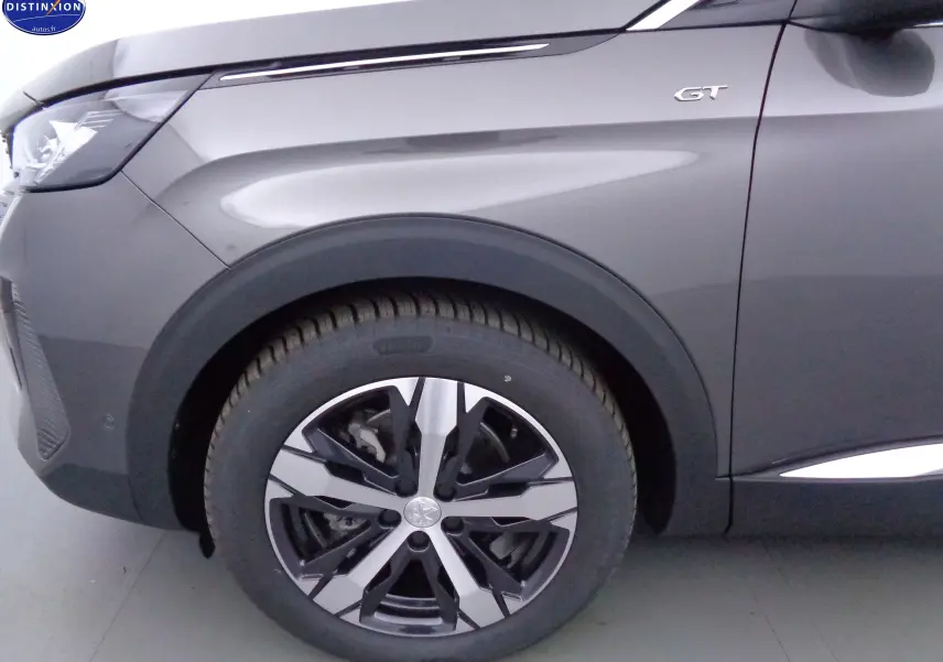 Gros plan sur la roue avant gauche et l'aile gris platinium métallisé d'un Peugeot 3008 GT 2023.