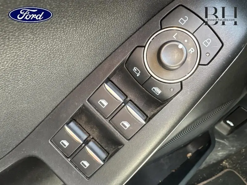 Gros plan sur les commandes des vitres et rétroviseurs côté conducteur d'une Ford Puma rouge 2022.