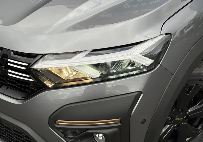 Gros plan sur l'avant droit gris schiste du Dacia Jogger 2025, mettant en valeur le phare LED et la jante noire.