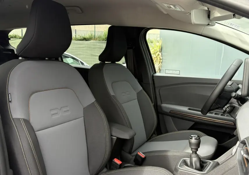 Intérieur avant du Dacia Jogger gris Schiste, sièges mixte TEP Micro Cloud avec surpiqûres brun cuivré et levier de vitesses manuel visible.