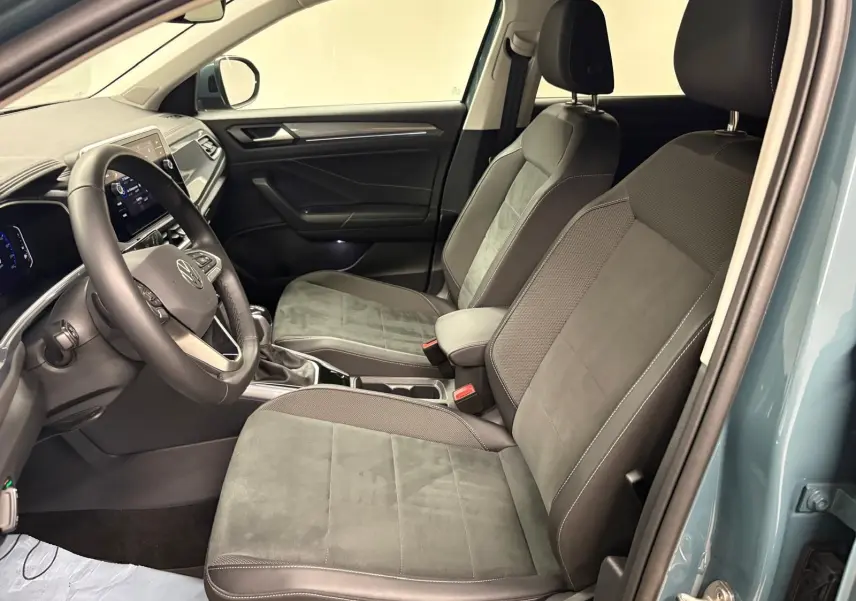 Vue intérieure côté conducteur du Volkswagen T-Roc 2025 bleu pétrole, sièges avant en tissu et volant multifonction.