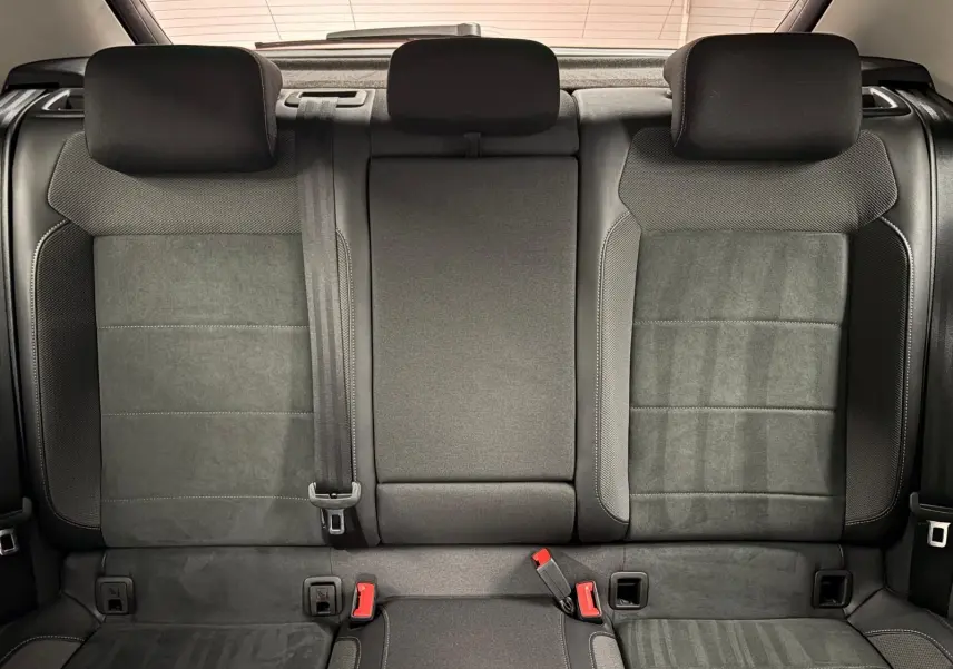 Vue intérieure des sièges arrière noirs du Volkswagen T-Roc 2025, avec appuie-têtes et ceintures visibles.