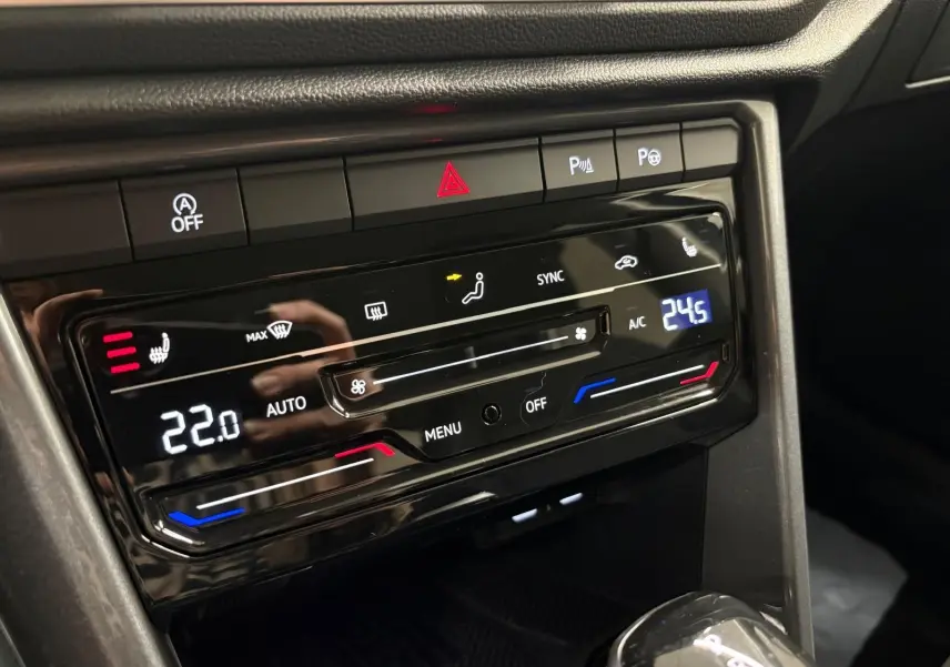 Gros plan sur la console centrale du Volkswagen T-Roc 2025, affichant la climatisation digitale et les commandes chauffantes.