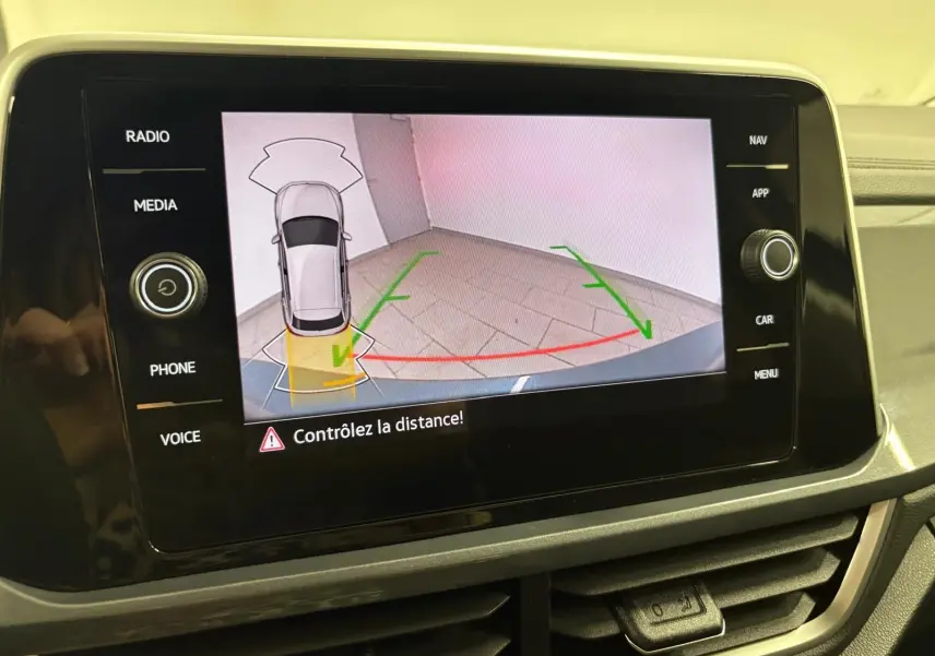 Écran central affichant la caméra de recul du Volkswagen T-Roc bleu pétrole avec guidage de trajectoire en intérieur.