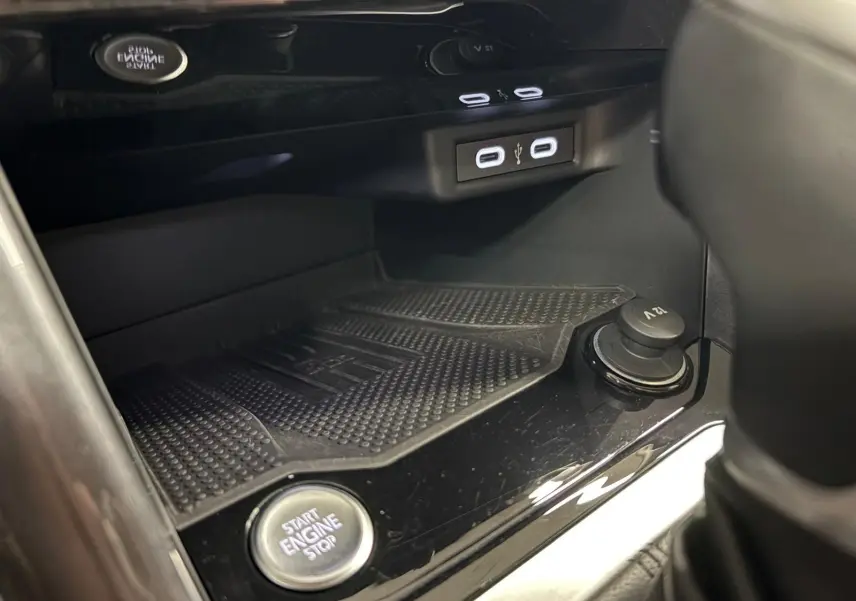 Gros plan sur la console centrale du Volkswagen T-Roc bleu pétrole, montrant le bouton start/stop et les ports USB.