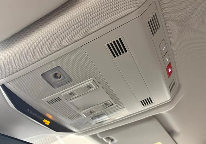 Plafonnier intérieur gris clair du Volkswagen T-Roc 2025 avec commandes d’éclairage et témoin airbag passager allumé.