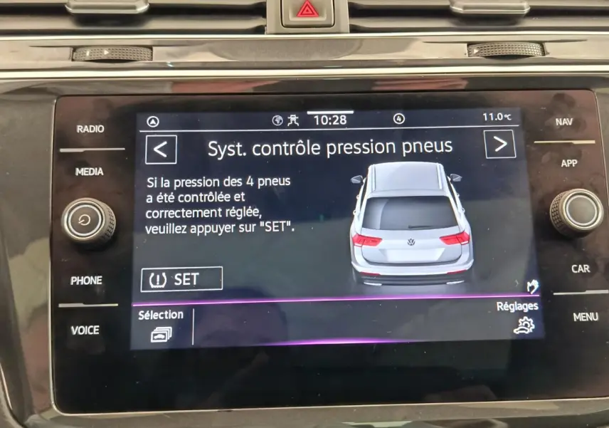 Écran tactile central affichant le contrôle pression pneus avec illustration arrière d'un Volkswagen Tiguan gris clair.