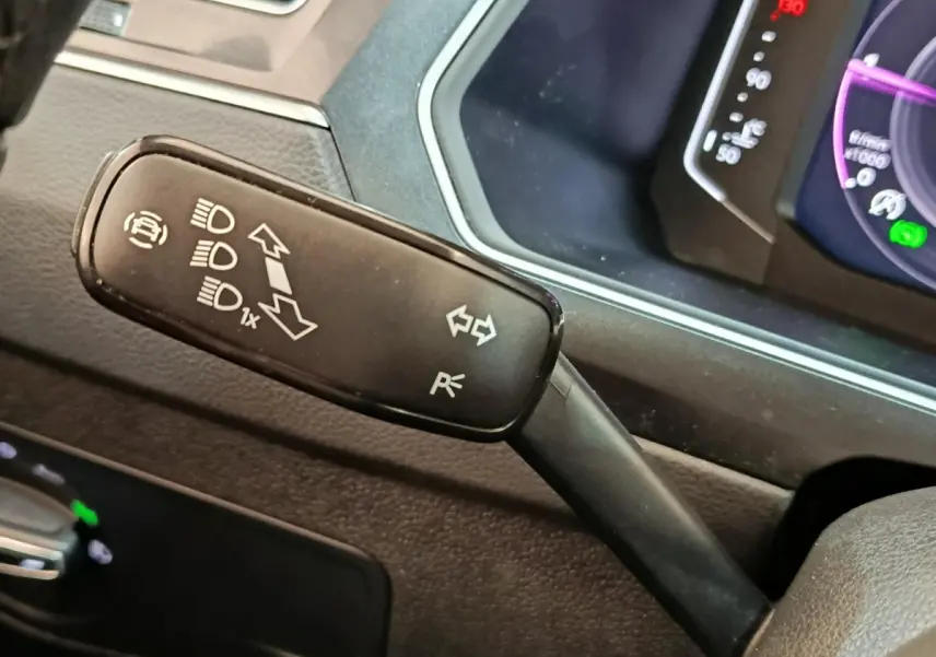 Gros plan sur la manette de clignotants noire à gauche du volant dans l’habitacle du Volkswagen Tiguan 2.0 TDI 2022.