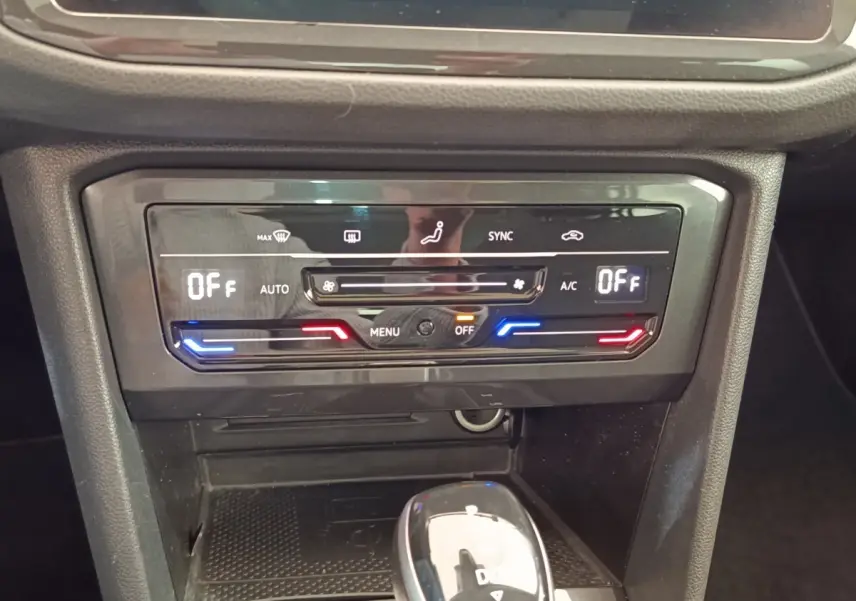 Gros plan sur la console centrale du Volkswagen Tiguan 2022, avec commandes climatisation et levier de vitesse noir brillant.