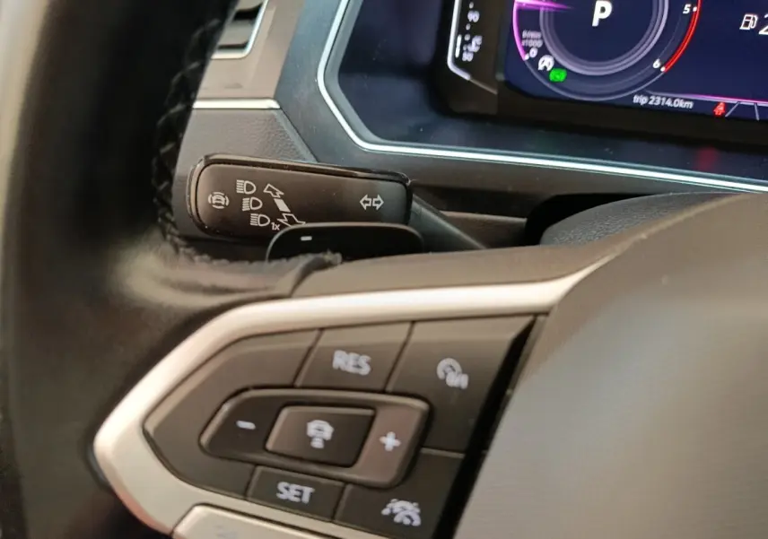 Gros plan sur le volant noir du Volkswagen Tiguan 2022, avec commandes du régulateur adaptatif et tableau de bord numérique.