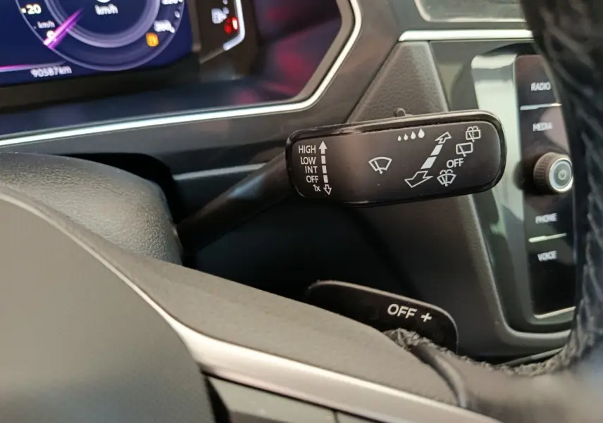 Gros plan sur la manette d'essuie-glace noire à gauche du volant dans l'habitacle du Volkswagen Tiguan 2022.