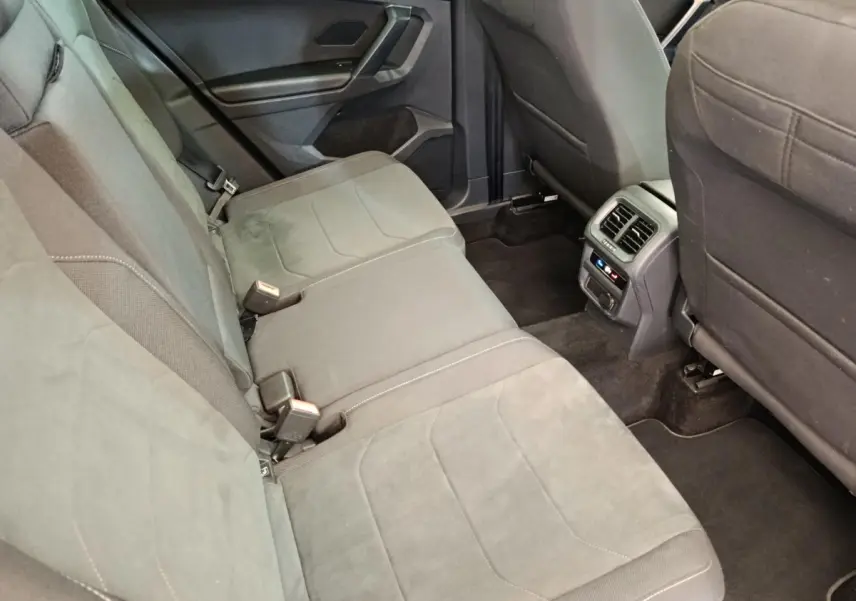 Vue intérieure arrière du Volkswagen Tiguan 2.0 TDI 150 DSG7 Elegance, sièges tissu gris et console centrale avec aérateurs.