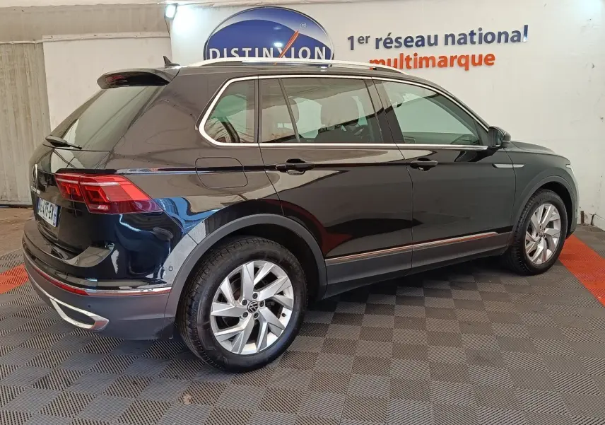 Vue 3/4 arrière droite d'un Volkswagen Tiguan noir brillant avec jantes alliage et feux arrière LED visibles.