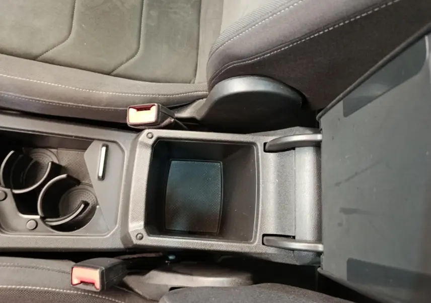 Vue rapprochée de la console centrale noire du Volkswagen Tiguan 2.0 TDI 150 DSG7 Elegance avec porte-gobelets et rangement ouvert.