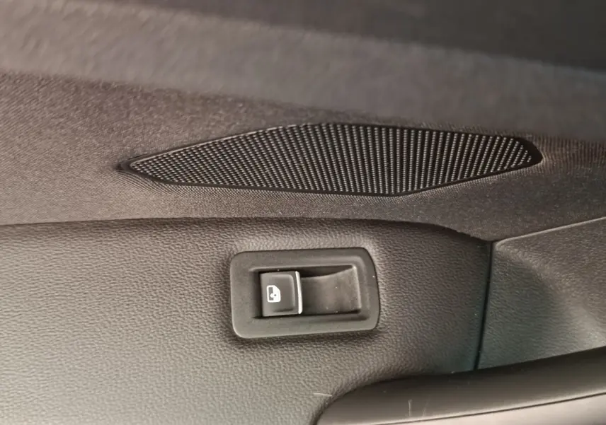 Détail intérieur du bouton d'ouverture électrique du coffre sur la porte arrière d'un Volkswagen Tiguan noir.