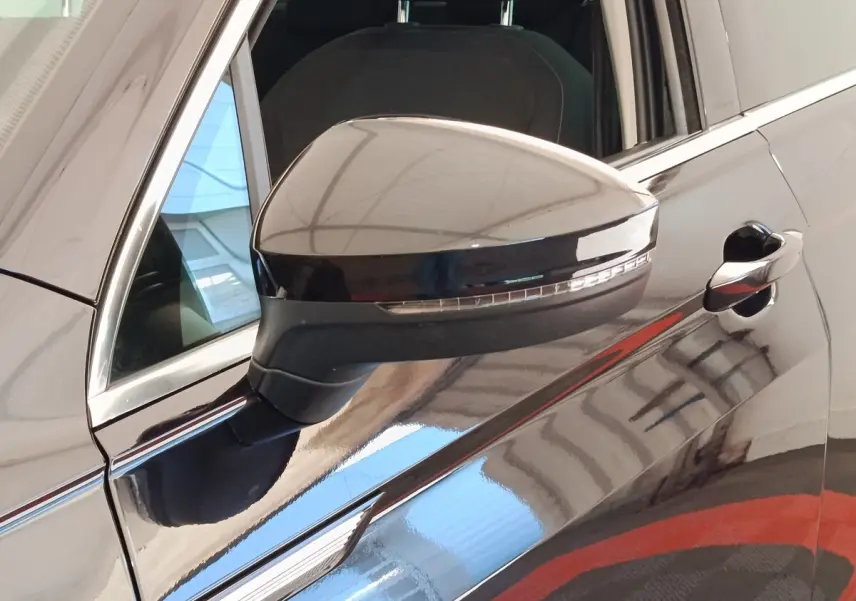 Rétroviseur côté gauche noir brillant du Volkswagen Tiguan 2.0 TDI 150 DSG7 Elegance 2022, avec porte et vitre partiellement visibles.