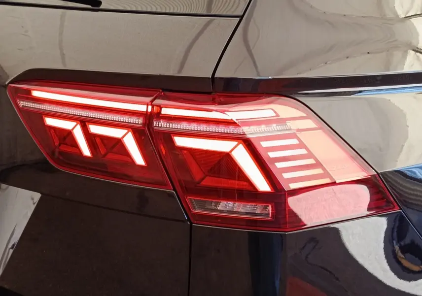 Gros plan sur le feu arrière droit allumé d’un Volkswagen Tiguan noir, soulignant les lignes LED distinctives.