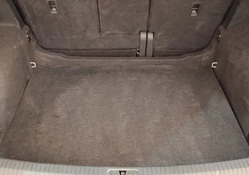Coffre vide du Volkswagen Tiguan 2.0 TDI 150 DSG7 Elegance, vue intérieure arrière avec moquette grise.