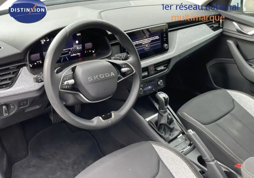Vue intérieure du poste de conduite du Skoda Kamiq blanc glacier 2025, avec volant multifonction et console centrale moderne.
