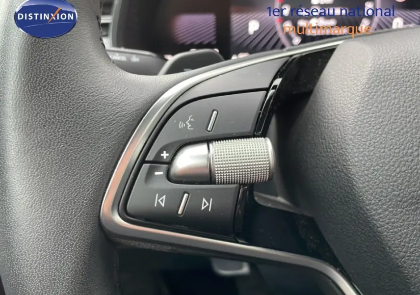 Gros plan sur les commandes au volant du Skoda Kamiq blanc glacier, mettant en valeur la molette de réglage et les boutons multifonctions.