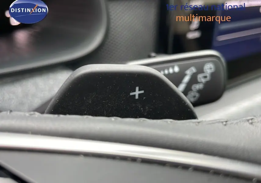 Gros plan sur la palette de changement de vitesse "+" au volant d'un Skoda Kamiq 2025, intérieur noir visible.