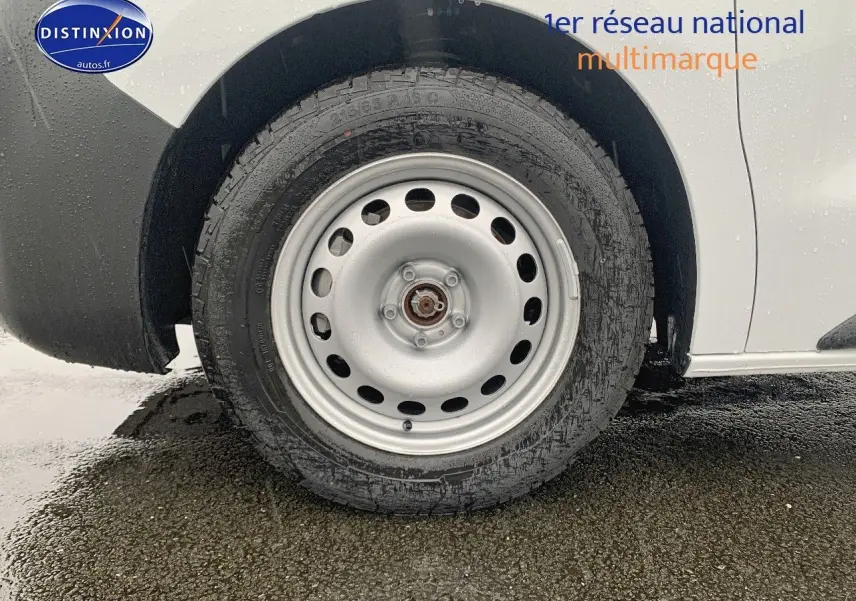 Gros plan sur la roue arrière droite d’un Peugeot Expert blanc Kaolin, soulignant la jante acier simple et le pneu humide.