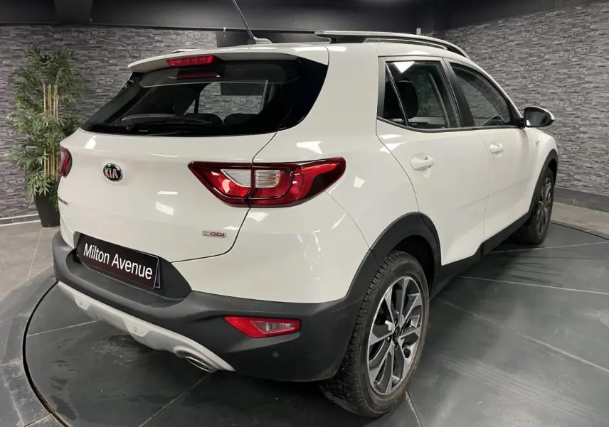 Vue 3/4 arrière droite d'un KIA Stonic blanc avec jantes alliage 17'' et protections noires sur les passages de roues.