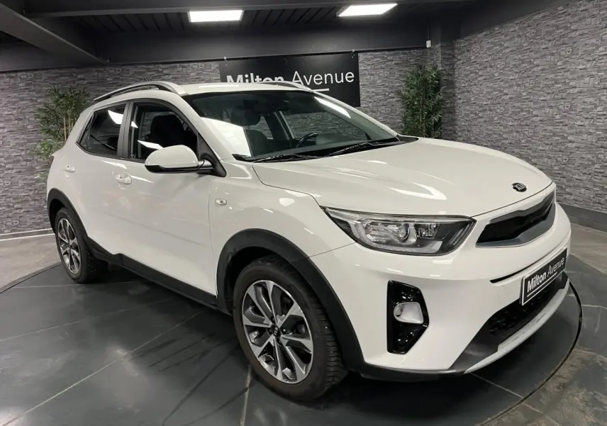 KIA Stonic blanc vue 3/4 avant droit avec jantes alliage et calandre noir laqué en intérieur showroom.