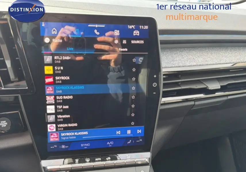 Écran tactile central du tableau de bord d'une Renault Espace noire, affichant les stations radio numériques.