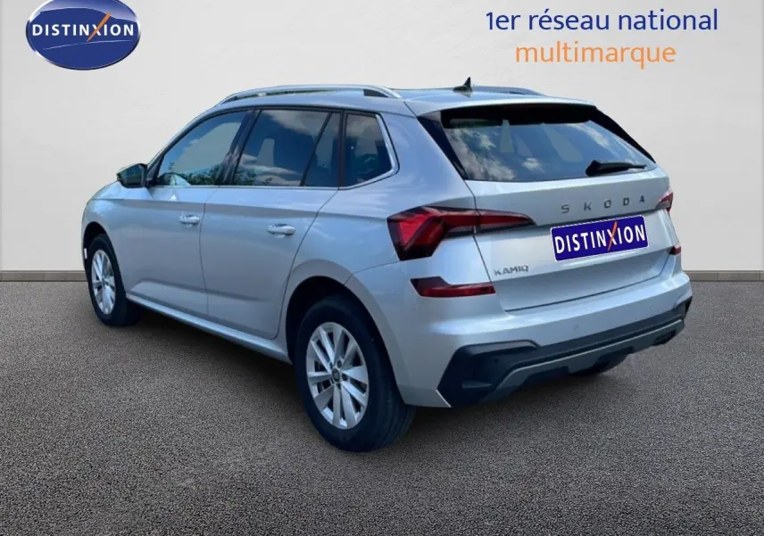 Vue 3/4 arrière droite du Skoda Kamiq gris argent métallisé avec feux arrière LED et toit avec barres de toit.