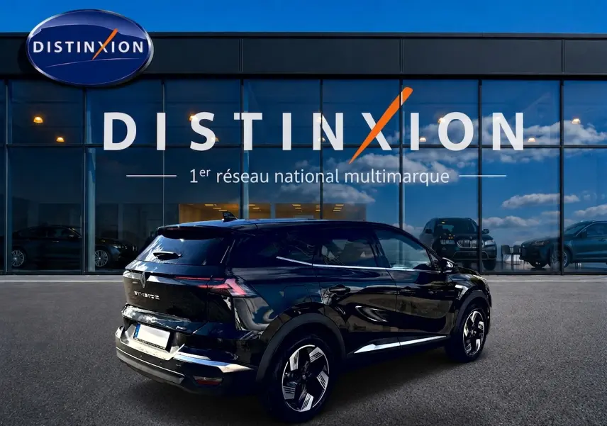 Vue 3/4 arrière droite d'un Renault Symbioz noir étoile avec jantes alu et feux arrière LED devant un showroom Distinxion.