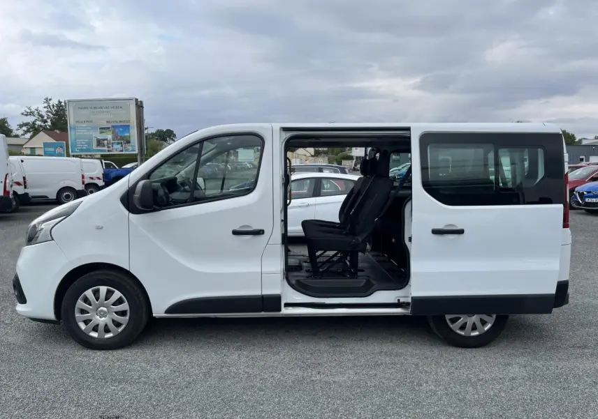 Profil côté gauche d'un Renault Trafic Fourgon blanc 2016 avec porte latérale coulissante ouverte et sièges noirs visibles.