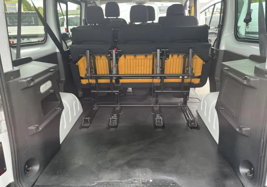 Vue arrière intérieure du Renault Trafic Fourgon blanc 2016 montrant la banquette arrière relevée et l'espace de chargement.