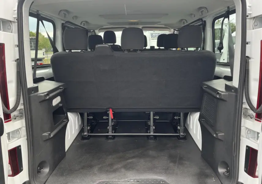 Vue arrière ouverte du Renault Trafic Fourgon blanc montrant la banquette arrière noire et l'espace de chargement vide.