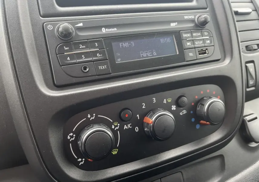 Tableau de bord noir du Renault Trafic Fourgon blanc 2016 montrant la radio et les commandes de climatisation.